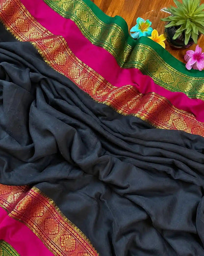 Black saree with pink and green border on a wooden surface